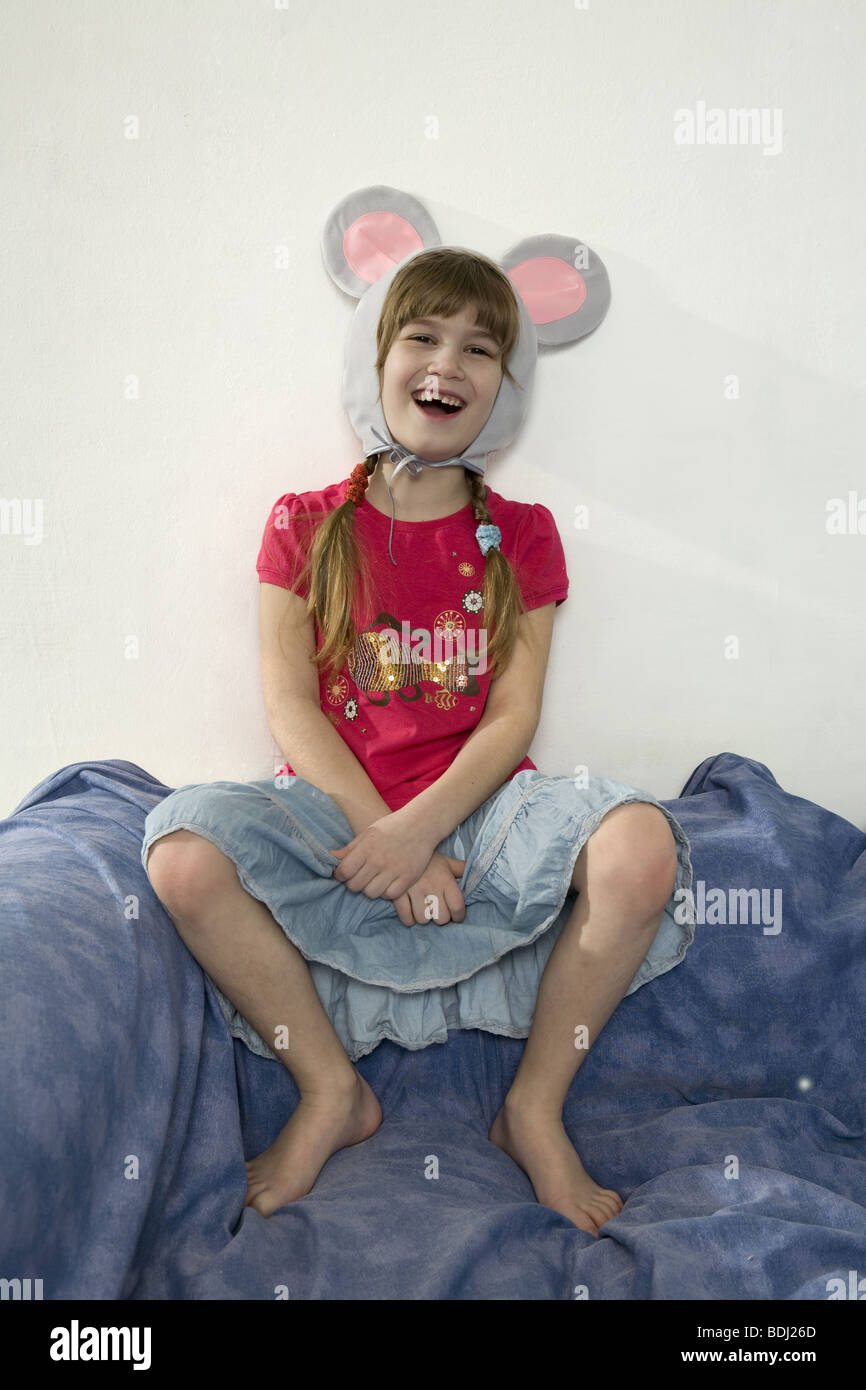 young cute laughing girl wearing mouses`s ears sitting on the sofa Stock Photo